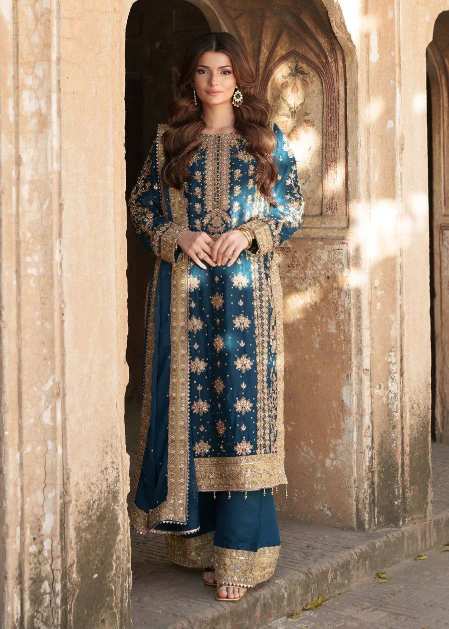 Woman in traditional blue and gold embroidered outfit standing in an archway.